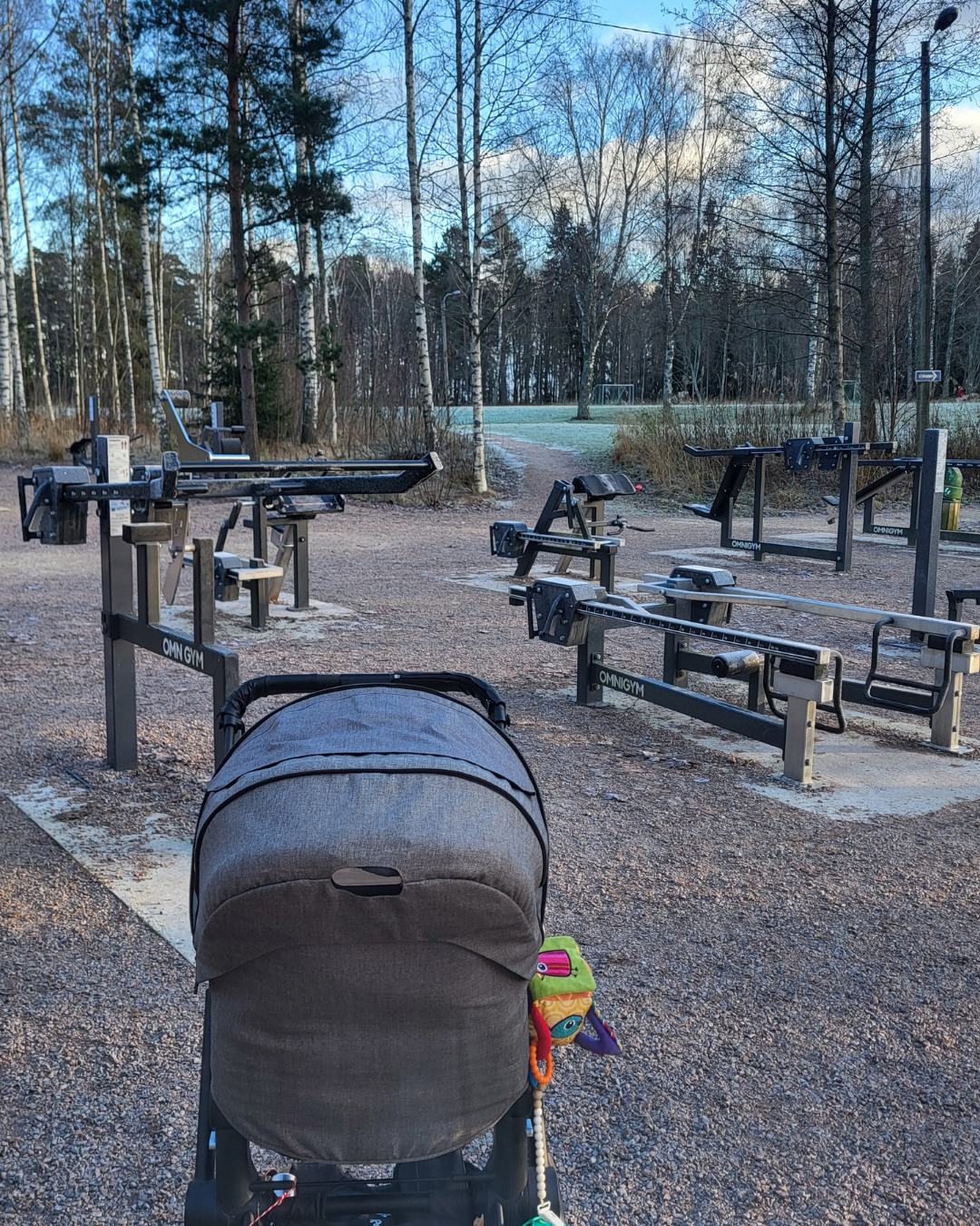 Kuva tyhjästä ulkosalista, jossa lastenvaunut etualalla, taustalla metsikköä ja ruohokenttä